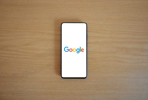 Photo showing A phone on a wooden platform showing Google on the screen. Indicating the evolution of search platforms in 2025.